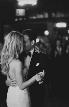 a bride and groom sharing a kiss on the dance floor at their wedding reception in black and white