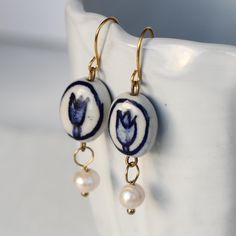 These beautifully painted tulip earrings feature a rich Delft blue on white porcelain with a glossy, glazed finish and a single freshwater pearl hanging below.  The earrings measure 45mm (just under two inches in length and have gold plated brass earwires.   🖤 FASTER SHIPPING 🖤 Need this fast? We offer a Faster Shipping option here: https://www.etsy.com/uk/listing/100107311/faster-shipping-priority-post-upgrade 🖤 GIFT MESSAGE & WRAP SERVICE! 🖤 https://www.etsy.com/uk/listing/750160511/gift-wrap-wrapping-personalised-card?ref=listings_manager_table Pearl Flower Earrings, Ceramic Charms, Manager Table, Busy Mind, Tulip Earrings, Porcelain Earrings, Blue Tulips, Ceramic Earrings, Ceramic Earring