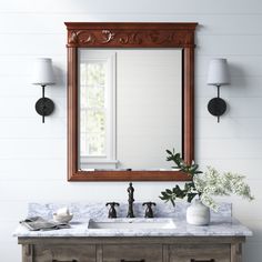 a bathroom vanity with a large mirror above it and two lights on the wall next to it