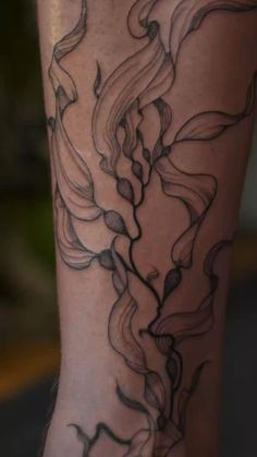 a woman's leg with black ink on it and flowers in the middle of her legs