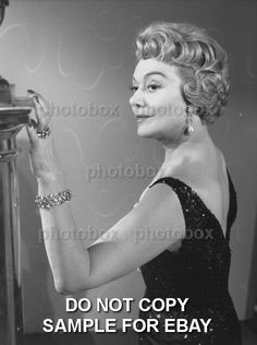 an old black and white photo of a woman with her hand on the top of a lamp