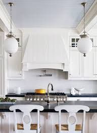 two white chairs sitting in front of a kitchen island with black counter tops and backs