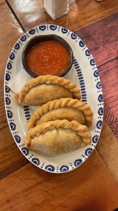 three pastries on a plate with dipping sauce