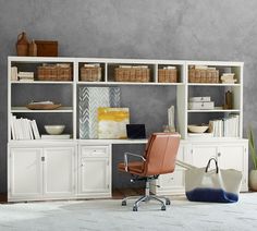 an office area with a desk, chair and bookcase in white painted wood finish