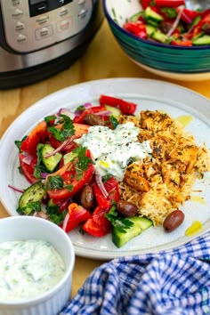 a white plate topped with vegetables and rice next to an instant pressure cooker filled with sauce