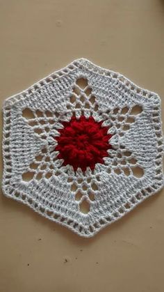 a white crocheted doily with a red flower on the center and bottom