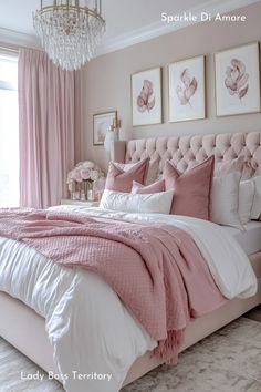 a bedroom with pink and white bedding, chandelier and pictures on the wall