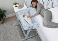 a woman laying on top of a bed next to a baby in a crib