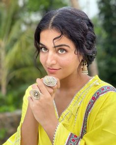 a woman in a yellow sari is posing for the camera with her hand on her face