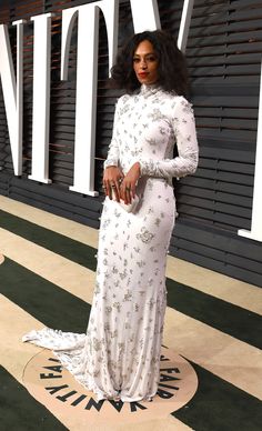 a woman in a white dress standing on a carpet with her hand on her hip