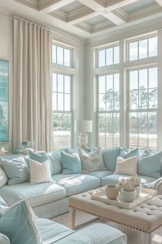 a living room filled with lots of furniture and large windows covered in white drapes