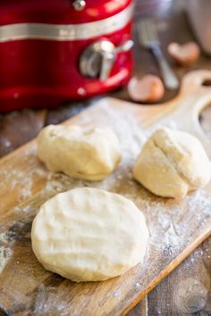 three uncooked doughnuts on a wooden cutting board