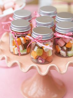 several jars filled with candy sitting on top of a cake plate