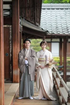 two people dressed in traditional japanese garb posing for a photo on a wooden platform