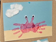 a child's handprinted picture of a crab on the beach with clouds in the background