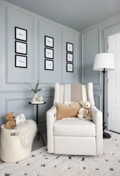 a white chair sitting in a living room next to a table with stuffed animals on it