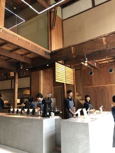 some people are standing at a counter in a restaurant with wood paneling and exposed ceilings