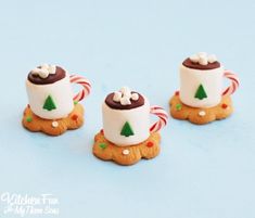 three small white and brown cups on top of each other with candy canes in them