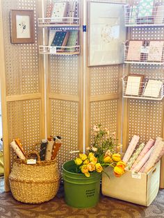 a room divider with baskets and flowers on the floor next to each other in front of it