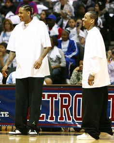 two men standing next to each other in front of a crowd at a basketball game