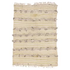 a beige and white striped rug with fringes on the bottom, in front of a white background