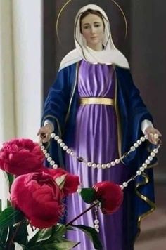 a statue of the virgin mary holding a rosary and flowers in front of her face