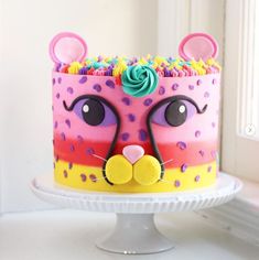 a birthday cake decorated to look like a cat's face with colorful frosting