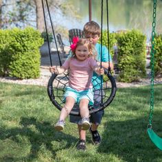 two children sitting on swings in the grass