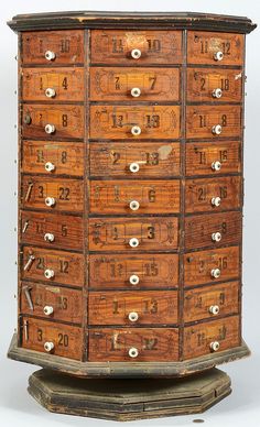 an old wooden cabinet with many drawers and numbers on the front, sitting on top of two pedestals