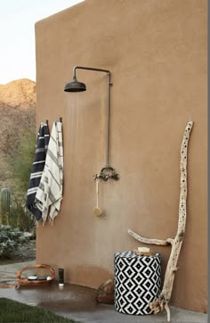 an outdoor shower with black and white towels hanging on it's wall next to a cactus