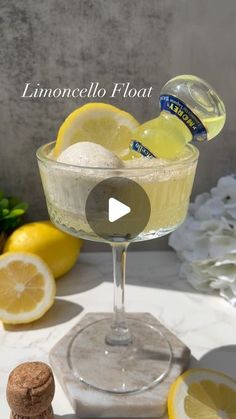 a glass filled with liquid and lemons on top of a white table next to some wine corks