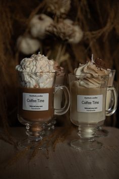 two coffee mugs filled with whipped cream and hot chocolate are sitting on a table