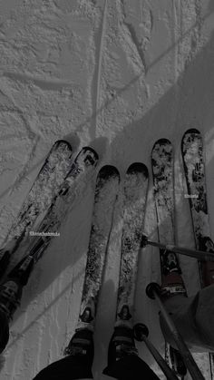 four skis and two snowboards are lined up on the ground in front of someone's feet