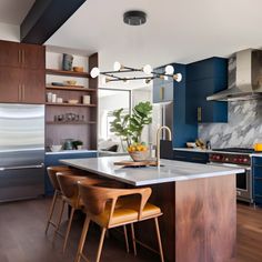 a kitchen with wooden floors and blue cabinets, marble counter tops and an island in the middle