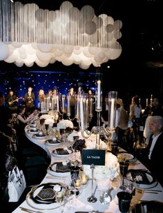 a long table is set up with white flowers and candles for an elegant dinner party