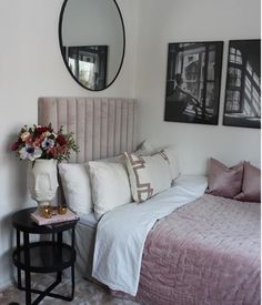 a bedroom with a bed, mirror and flowers on the side table in front of it