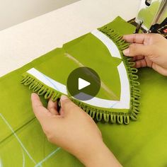 someone is using scissors to cut fabric on a green table cloth that has an eye design