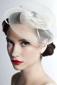 a woman wearing a white hat with flowers on it's brim and red lipstick