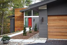 a house with two garages in front of it and trees around the outside area