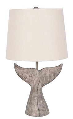 a table lamp with a whale tail design on the base and a white shade over it