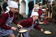 some people are walking down the street with pans in their hands and one is wearing an apron