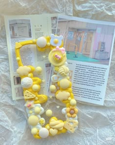 the letter e is made out of yellow and white plastic beads with flowers on them