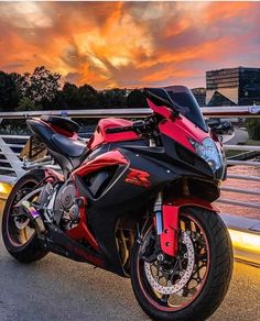 a red and black motorcycle parked on the side of a road next to a bridge