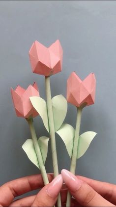 a person holding three paper flowers in their hands