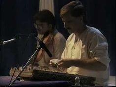 two men playing musical instruments in front of microphones