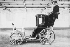 an old black and white photo of a man in a top hat sitting on a horse drawn carriage