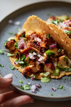 two tacos are sitting on a plate with onions and cilantro garnish