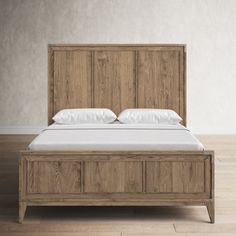 a bed with white pillows and wooden headboard in a room that has hardwood floors