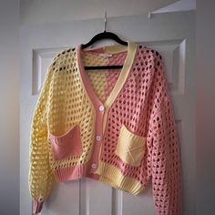 a pink and yellow sweater hanging on a door