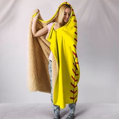 a woman wearing a yellow hooded blanket with red stitchs and baseball stitches on it